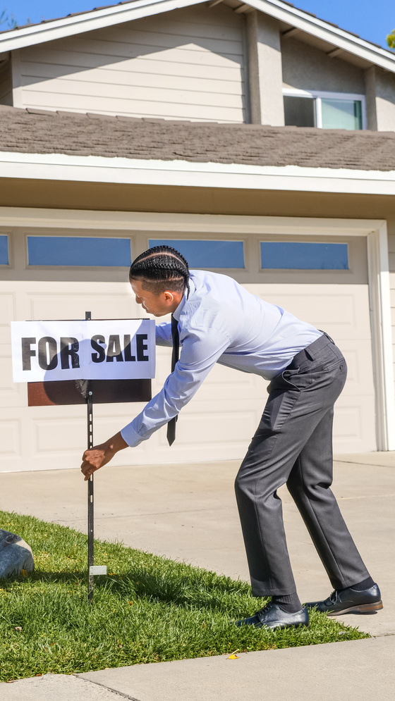 Man Fixing a For Sale Sign